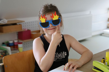 Mädchen trägt gebastelte Sonnenbrille mit Flammen