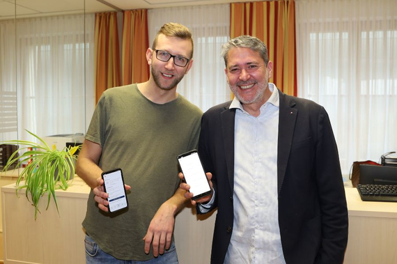 Meldeamtsleiter Sascha Rieger und Stadtamtsdirektor Markus Tod zeigen ID Austria auf ihren Mobiltelefonen.