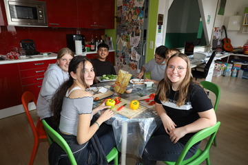 Eine Gruppe Jugendliche sitzen am Tisch.
