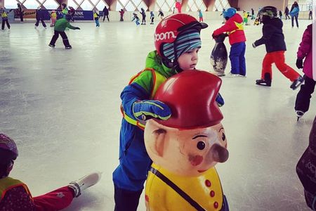 Ein Kleinkind am Schiebe-Pinguin auf dem Eis.