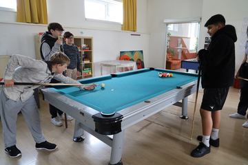 Eine Gruppe Teenager beim Billardspielen.