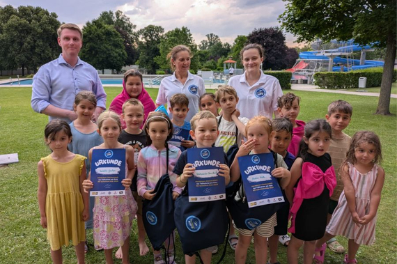 Gruppenfoto mit den Kindern, die den Schwimmkurs absolvierten. Sie halten alle eine Urkunde. Dahinter stehen die Mitglieder des ÖWR