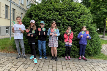 Kinder halten selbstgebastelte Schilder mit Daumen hoch und Daumen runter in die Kamera