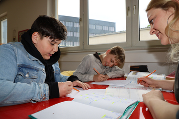 Zwei Teenager sitzen am Tisch und machen ihre Hausaufgaben.