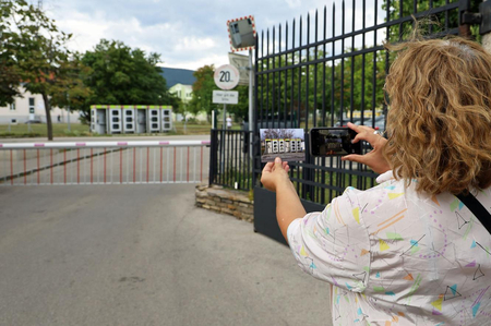 Künstlerin mit Postkarte vor Telefonzellen.