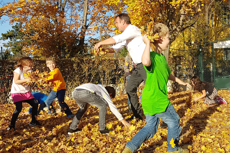 Andi Babler und eine Gruppe Kinder bewerfen sich im Schulhof mit Laub.