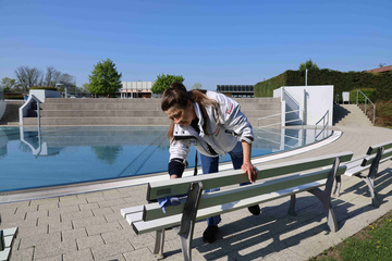 Mitarbeiterin reinigt eine Sitzbank