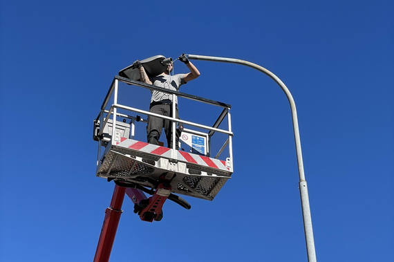 Elektriker auf Kran, der Straßenbeleuchtung wechselt