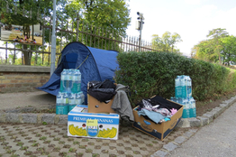 Ein kleines Mahnmal aus Zelt, Wasserflaschen und Kartons mit Kleidung vor der Erstaufnahmestelle Ost.