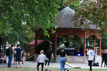 Tanzende Besucher halten Abstand vor dem Pavillon.