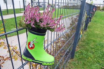 Gartenzaun mit bepflanzten alten Gummistiefel.