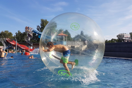 Jugendlicher in großer Plastikkugel im Schwimmbecken.