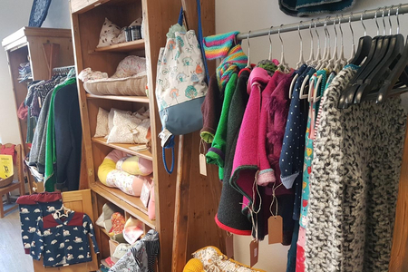 Baby-Kleidung und Hundebetten in einem offenen Schrank